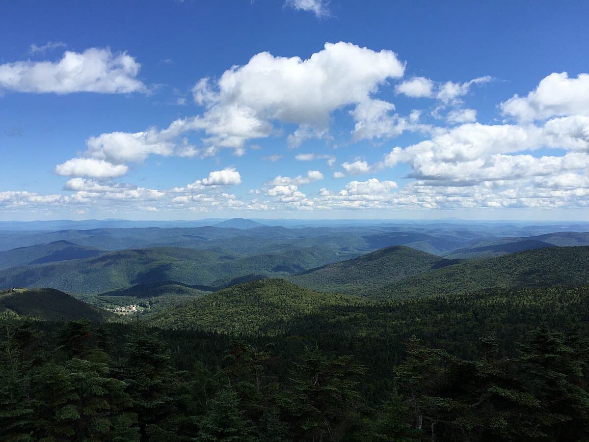 Panoramic view from Killington Peak looking out over the rolling Green Mountains of Vermont under blue skies